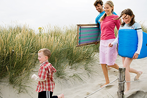 Family carrying beach equipment on way to the beach