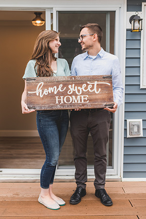 Happy couple holding a Home Sweet Home sign after successfully navigating the Seaside Park real estate market