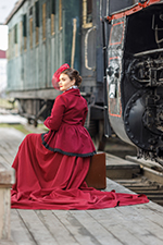 Woman in historical dress sitting on a suitcase by a train waiting to get to her Seaside Park rental